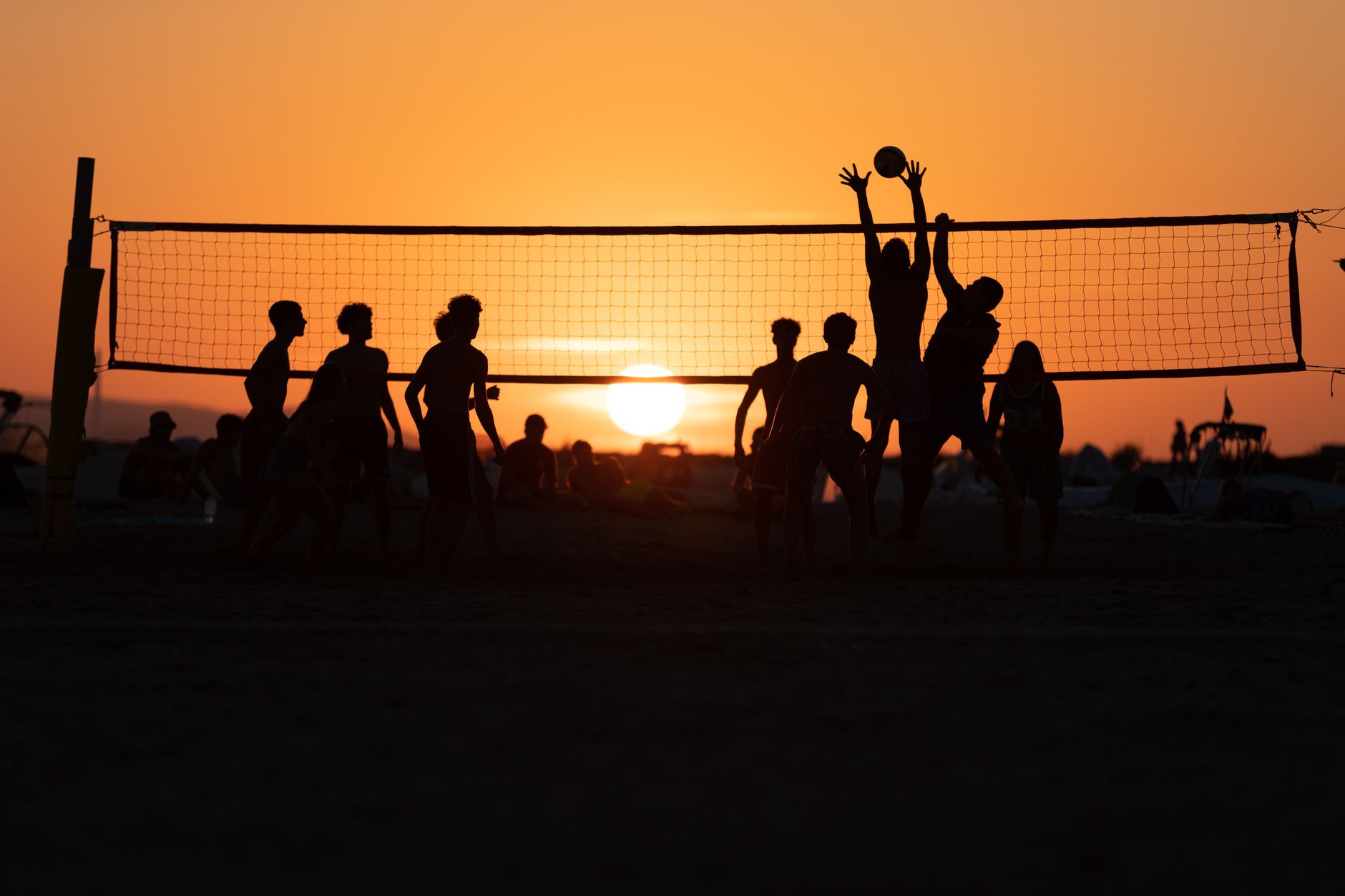Beach volleyball game at sunset