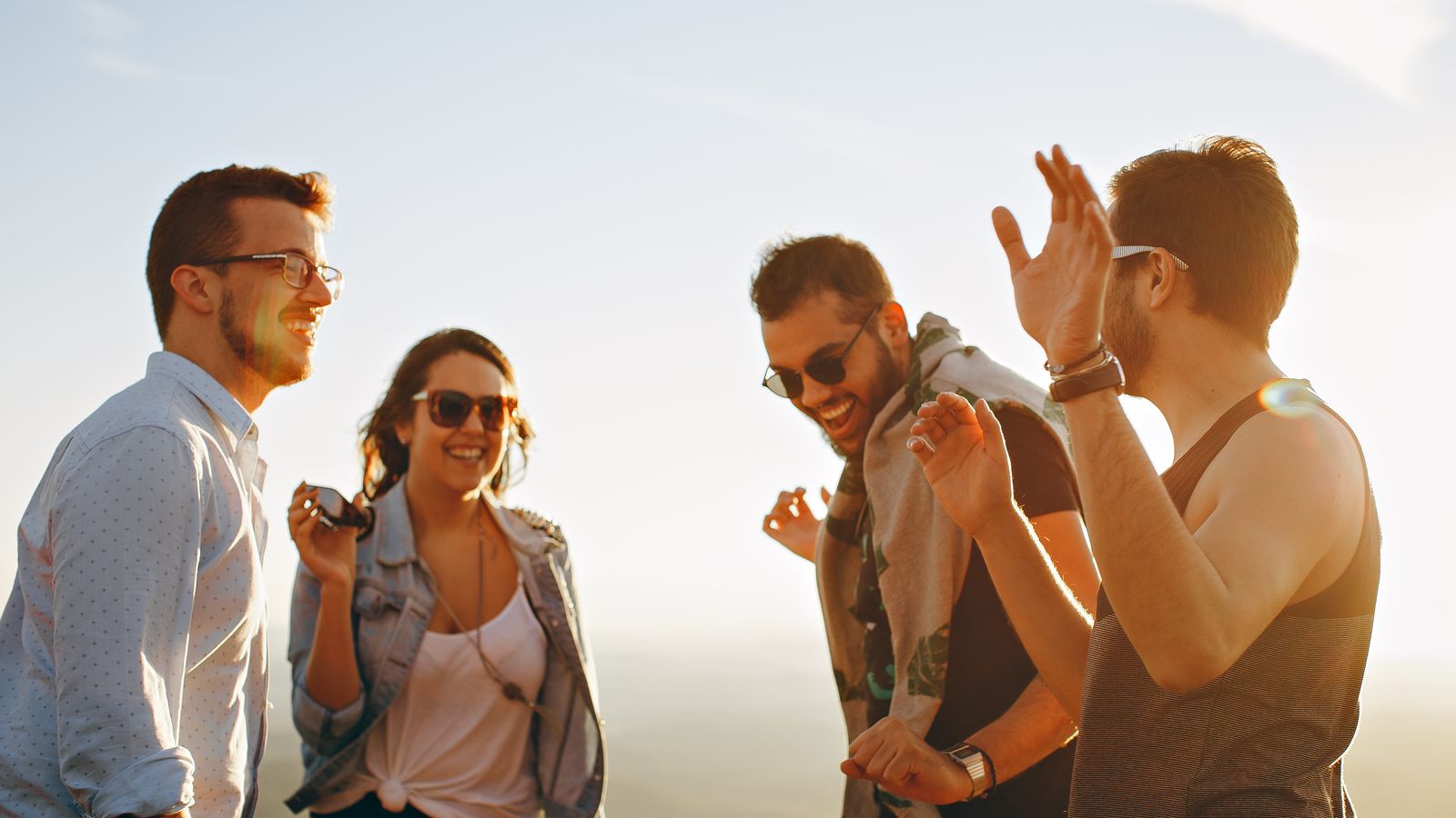 A diverse group of friends laughing together outdoors in the sun