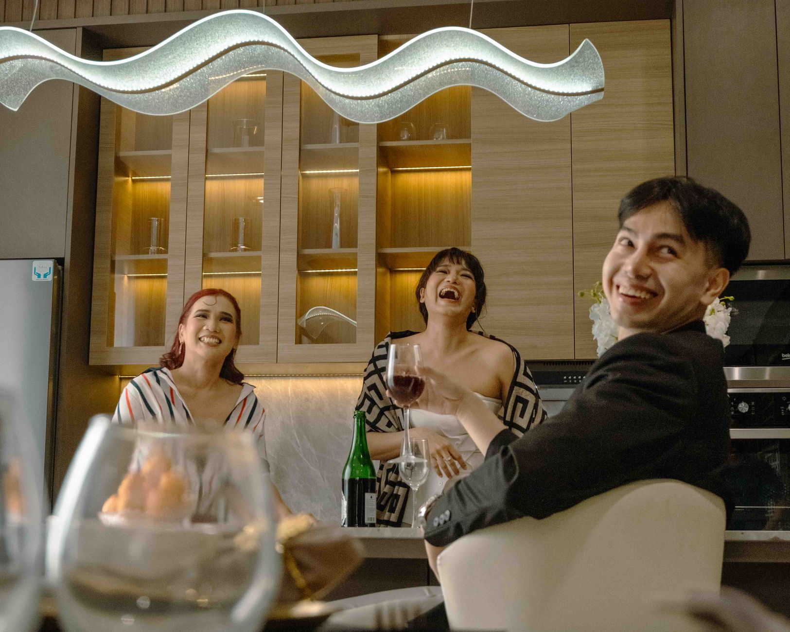 Friends laughing around an outdoor dinner table in the evening