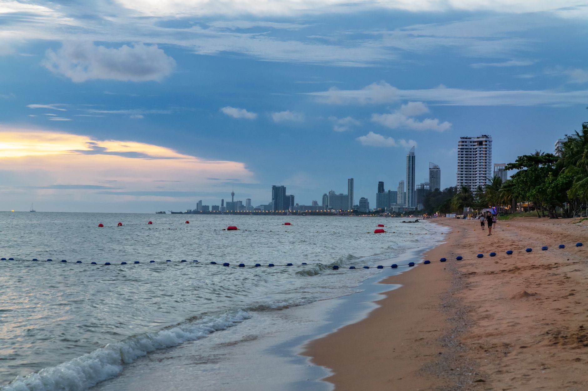 Pattaya beachfront at sunset with palms along the promenade